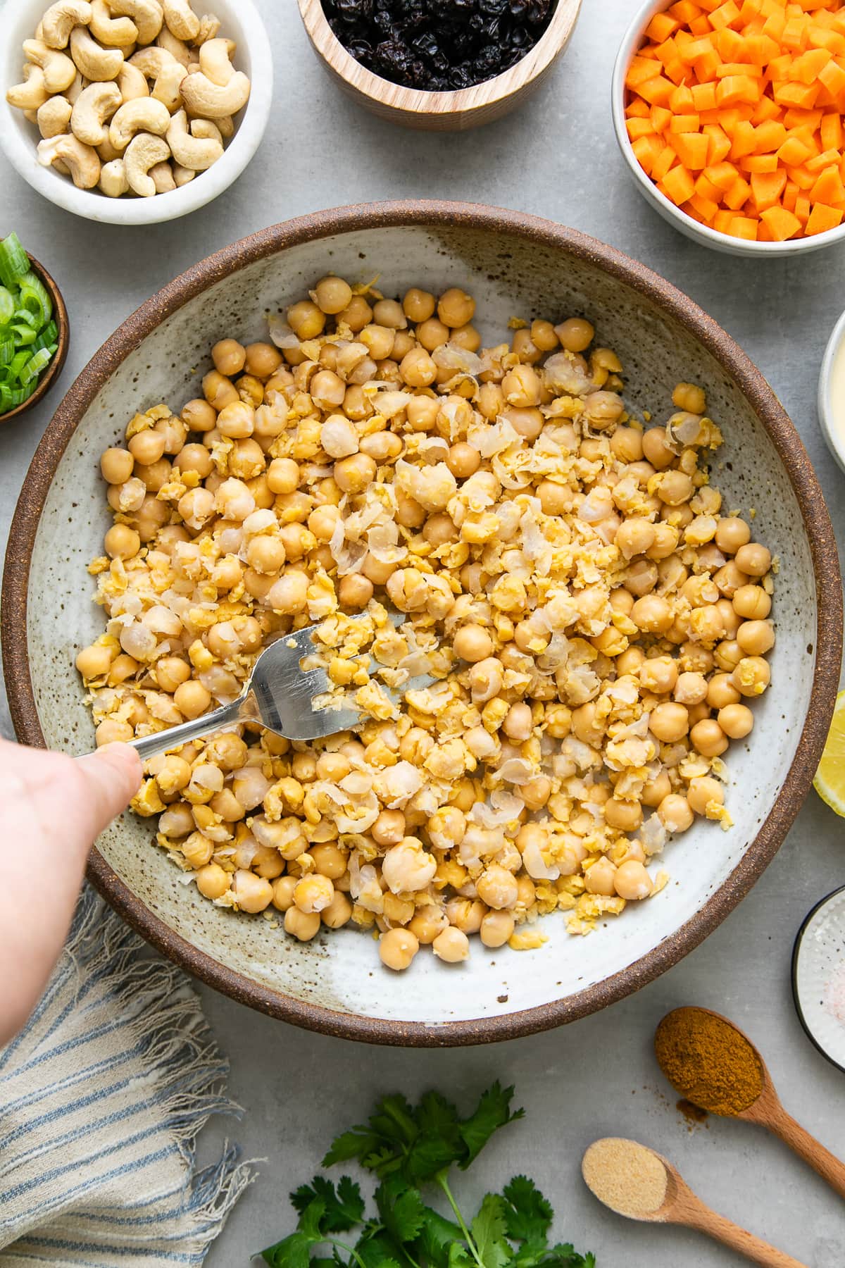 top down view showing the process of mashing chickpeas with items surrounding.
