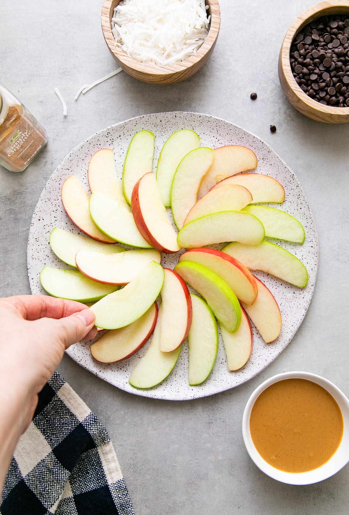 top down view showing the process of layering apples on plate with items surrounding.