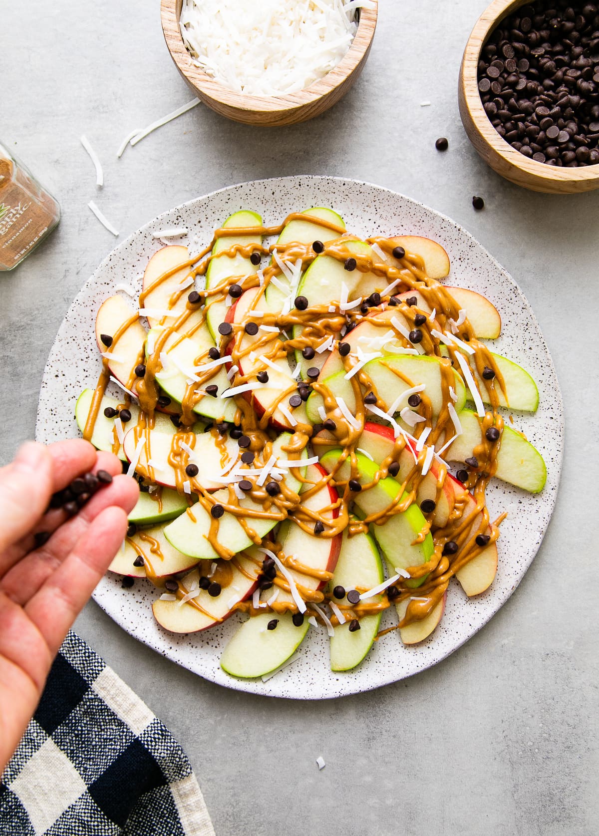 top down view showing the process of layering apple nachos on a plate with items surrounding.