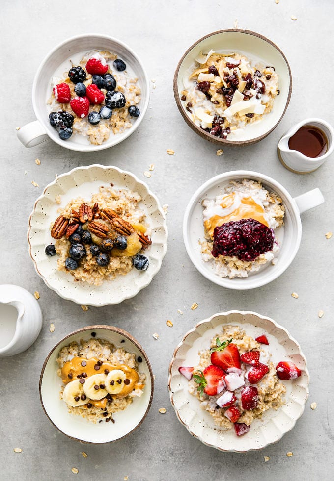 top down view of 6 bowls of healthy oatmeal with various toppings.
