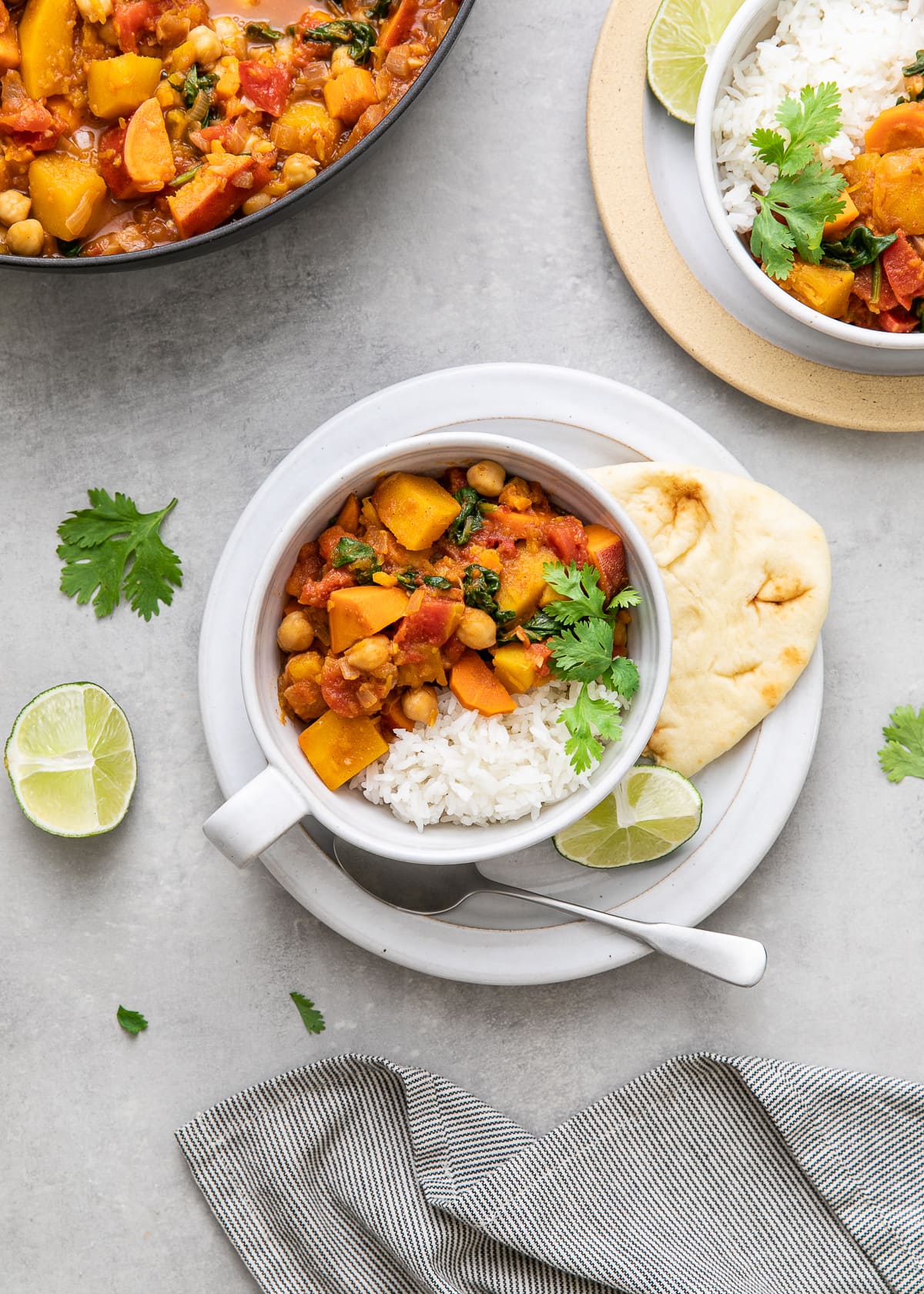 top down view of bowl with serving of moroccan pumpkin and chickpea stew with rice and items surrounding.