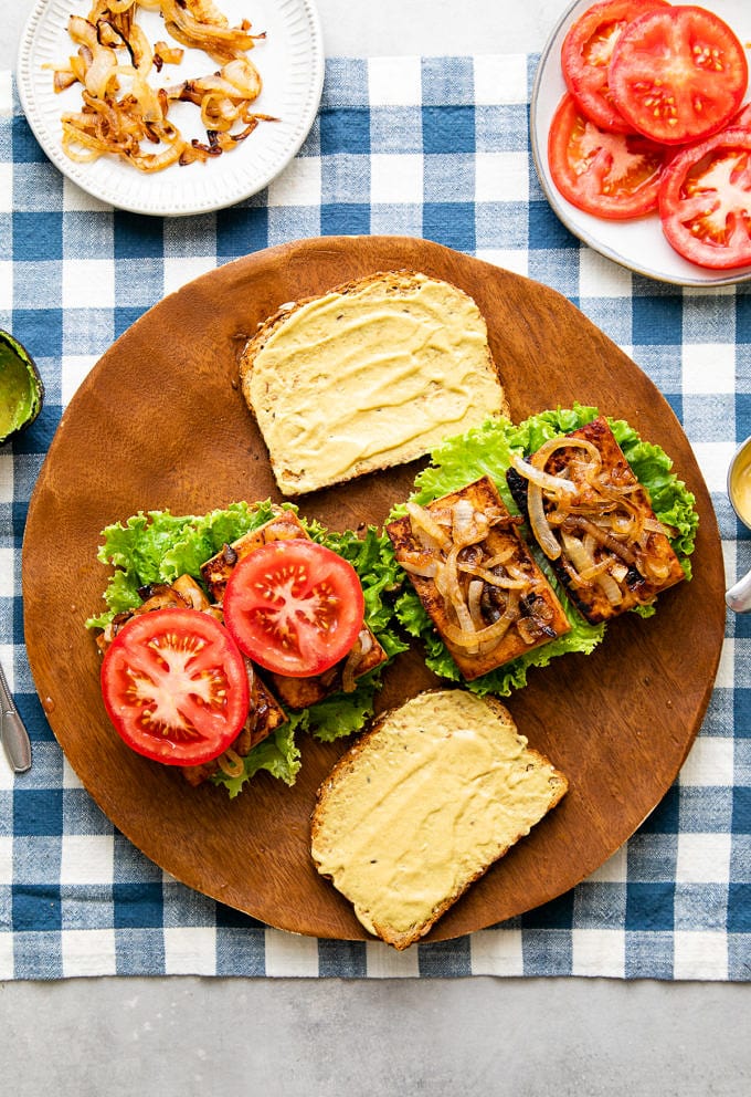 top down view showing the process of layering tofu sandwich with ingredients.