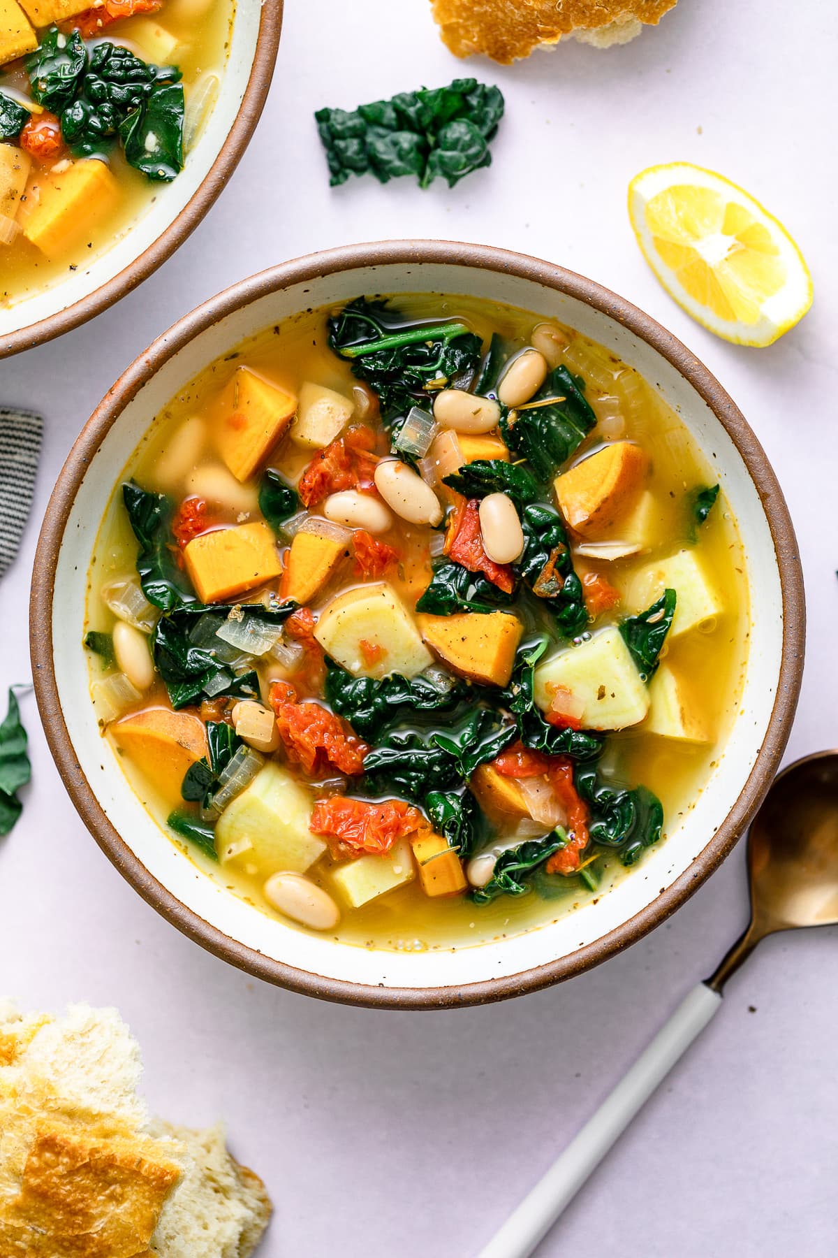 top down view of healthy sweet potato kale soup in a bowl with items surrounding.