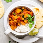 top down view of bowl with serving of moroccan pumpkin and chickpea stew with rice and items surrounding.