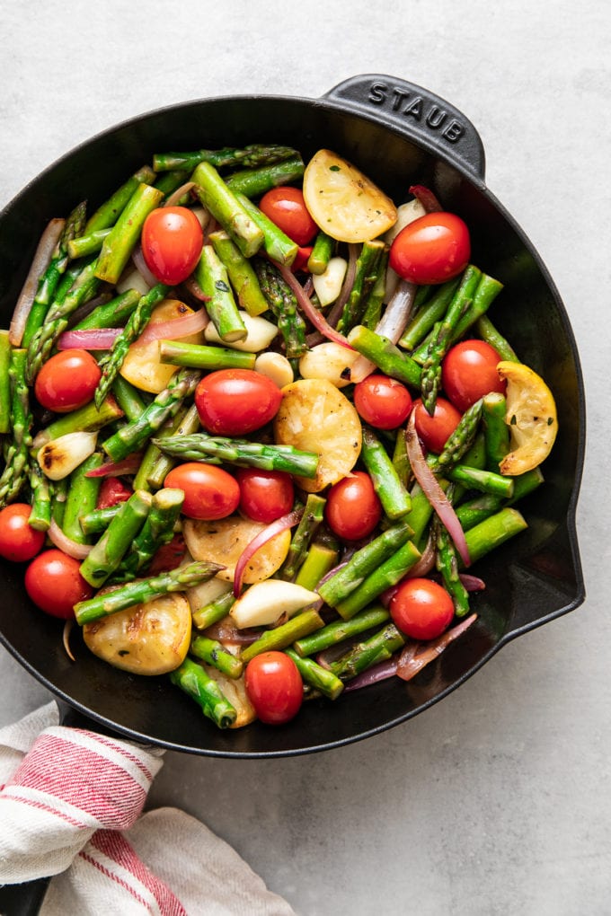 top down view of freshly cooked asparagus and tomato medley in a skillet.